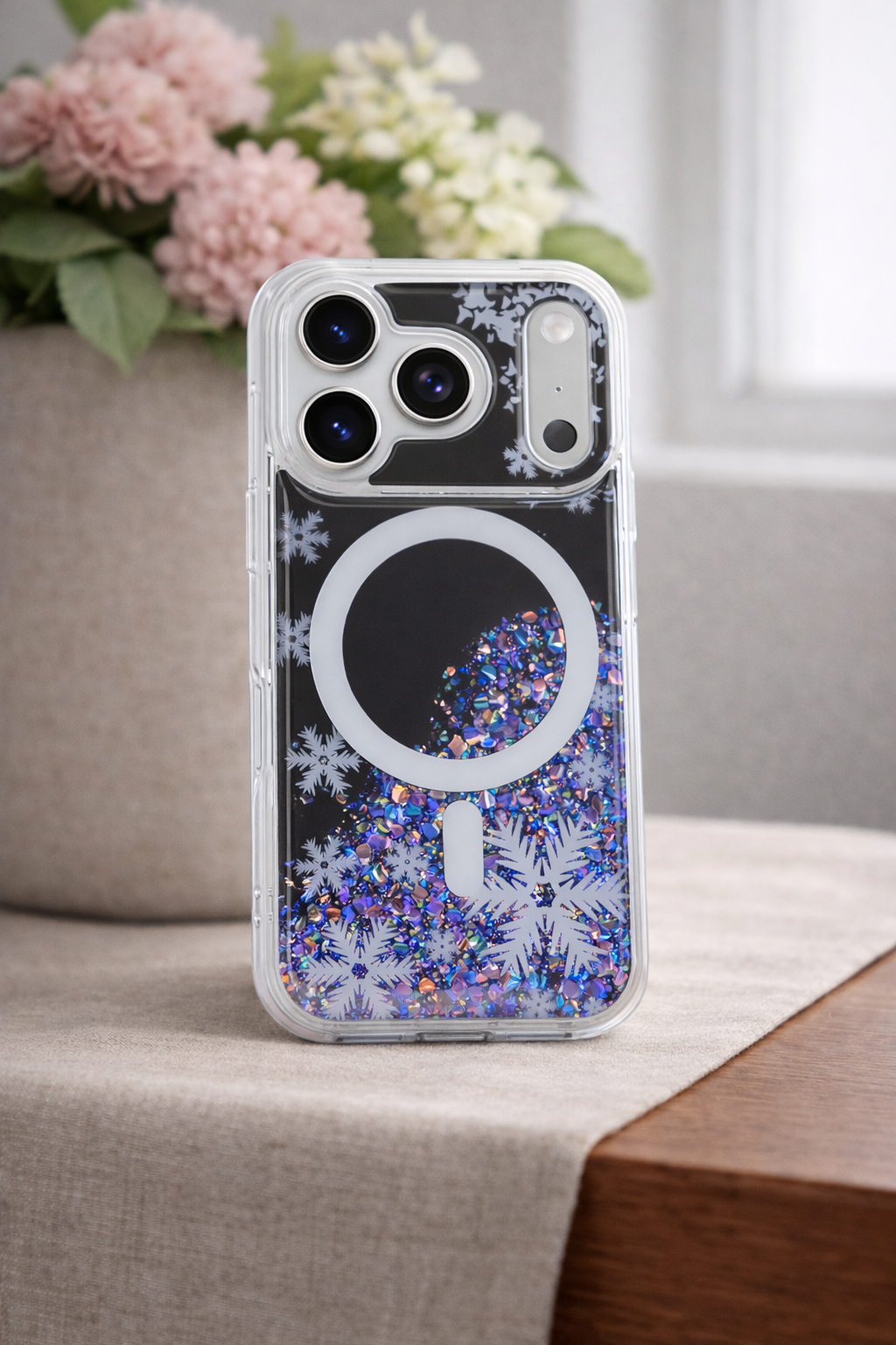Phone case with glittery design on a surface with flowers in the background