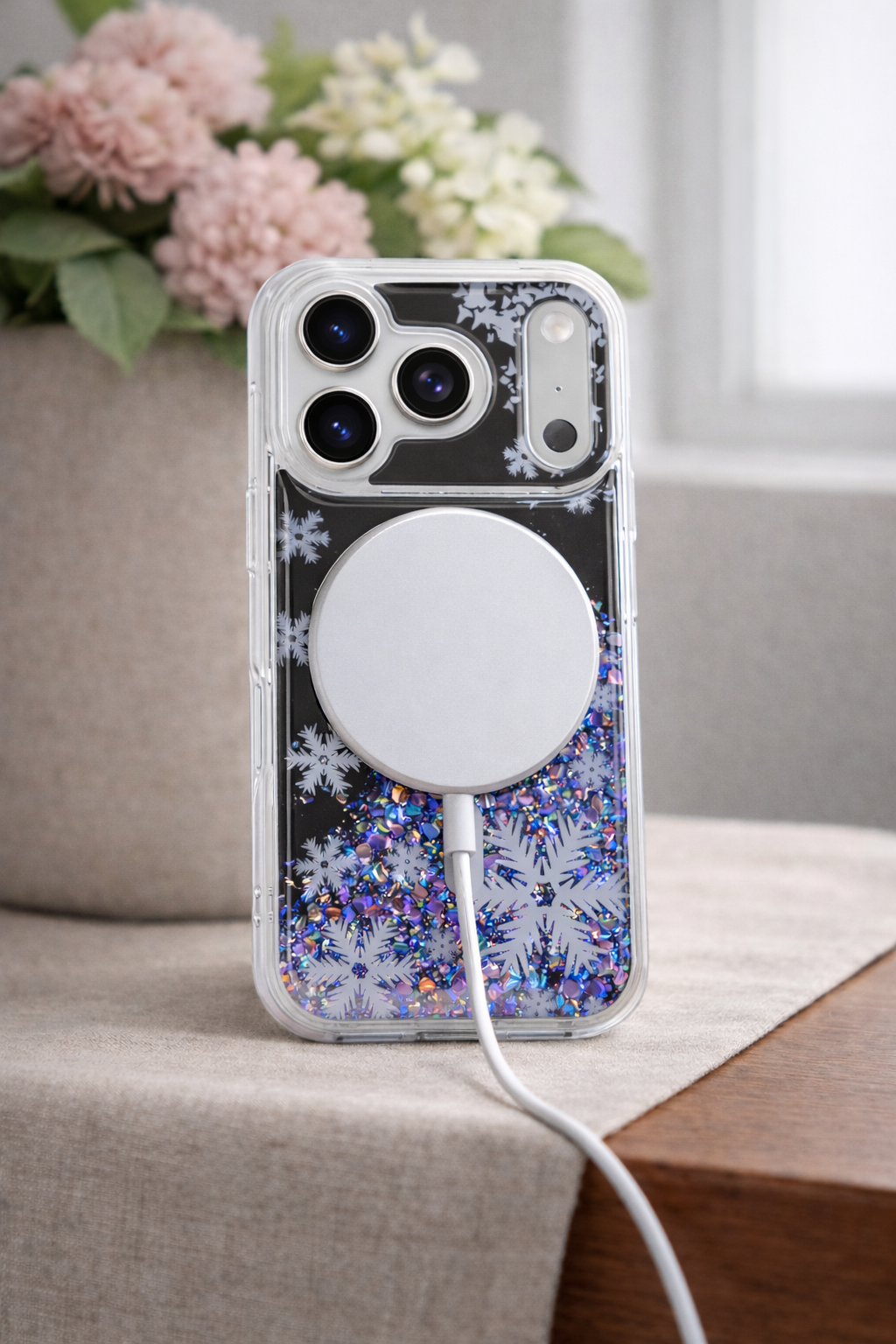 Phone case with floral design and magnetic charging pad on a surface with flowers in the background