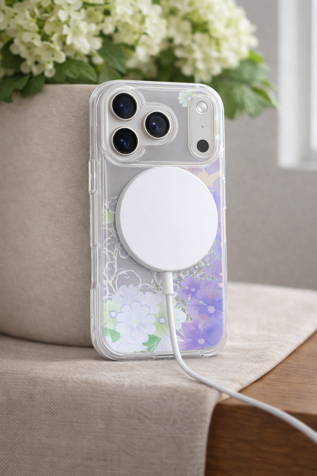Phone case with a floral design and magnetic pop socket on a surface with flowers in the background