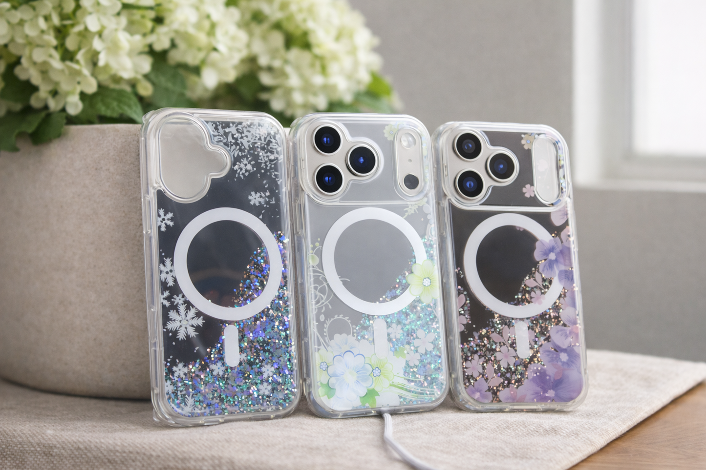Three phone cases with floral designs on a surface with flowers in the background